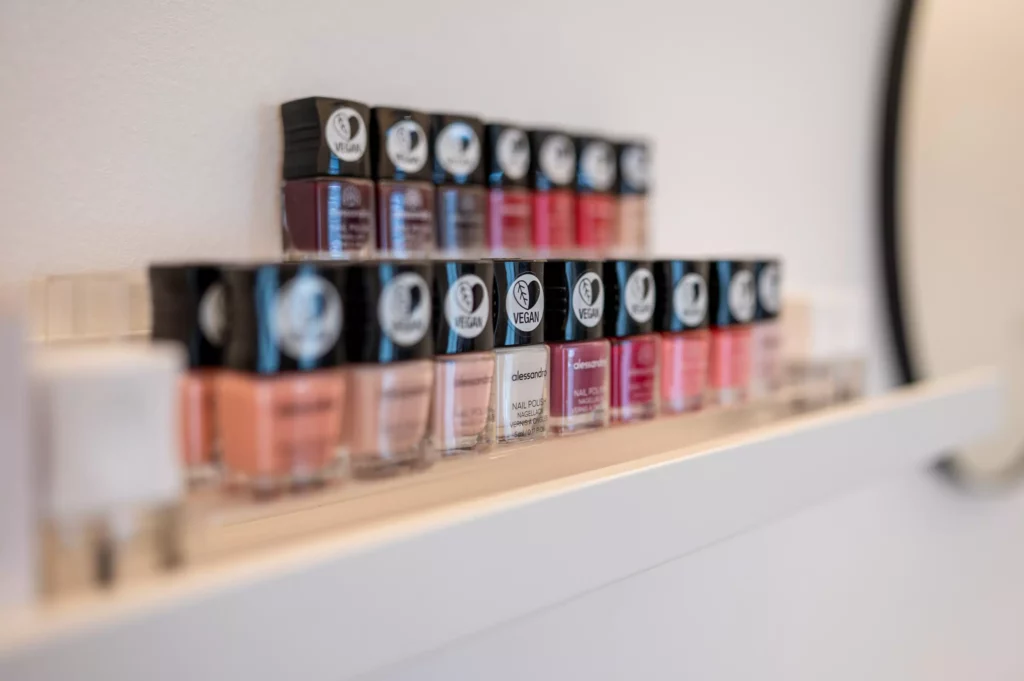 Reihe von veganen Nagellackflaschen in verschiedenen Farben auf einem weißen Regal im Gesundheitszentrum Radstadt