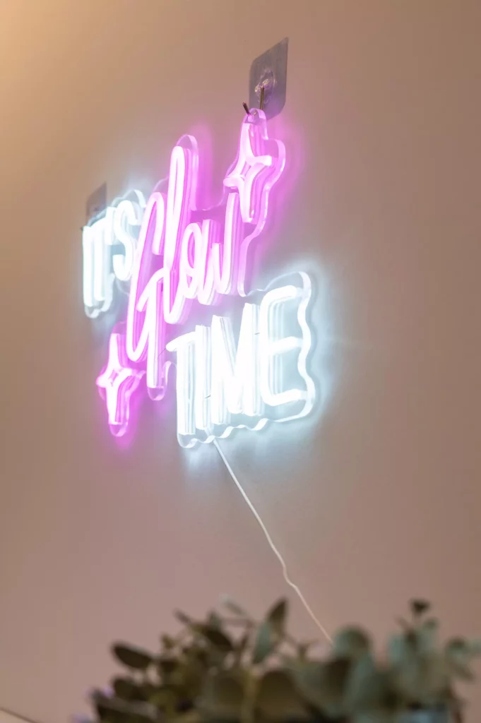 Leuchtendes Neon-Schild an Wand mit Schriftzug It’s Glow Time in Weiß und Pink im Gesundheitszentrum Radstadt