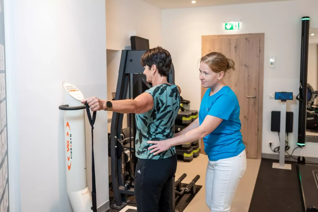 Physiotherapeutin unterstützt Patientin bei Übung an Vibrationsgerät im Gesundheitszentrum Radstadt