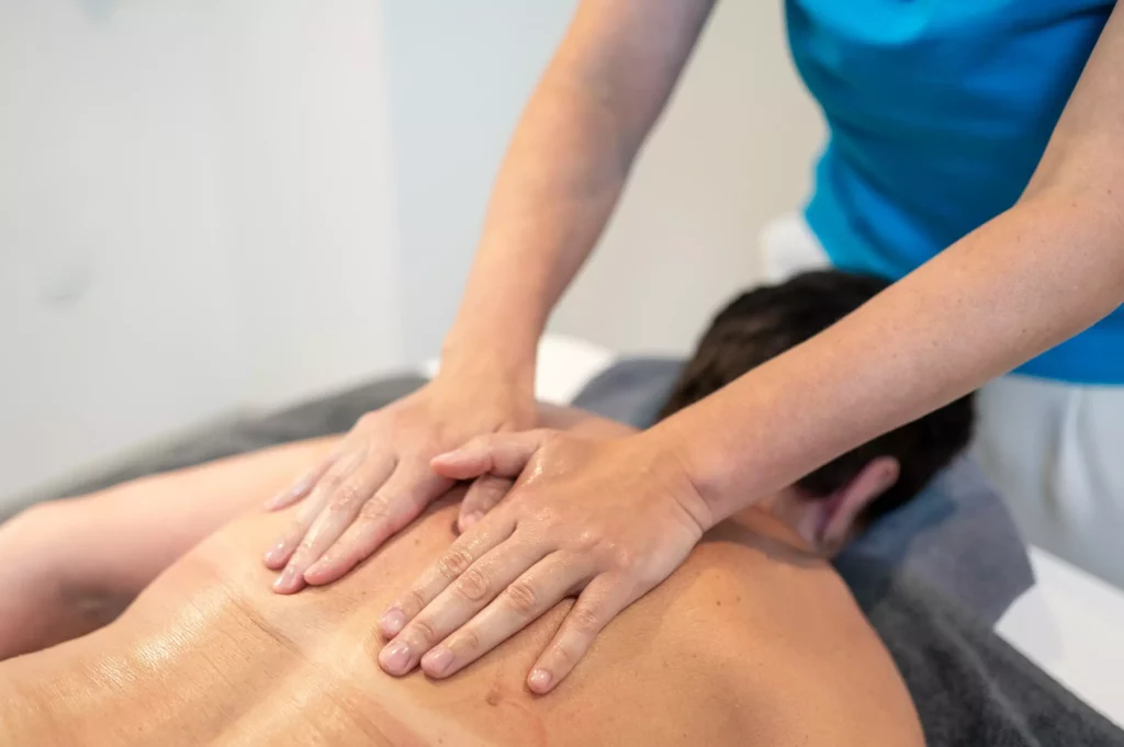Massagebehandlung im Gesundheitszentrum Radstadt mit Händen auf dem Rücken eines liegenden Patienten