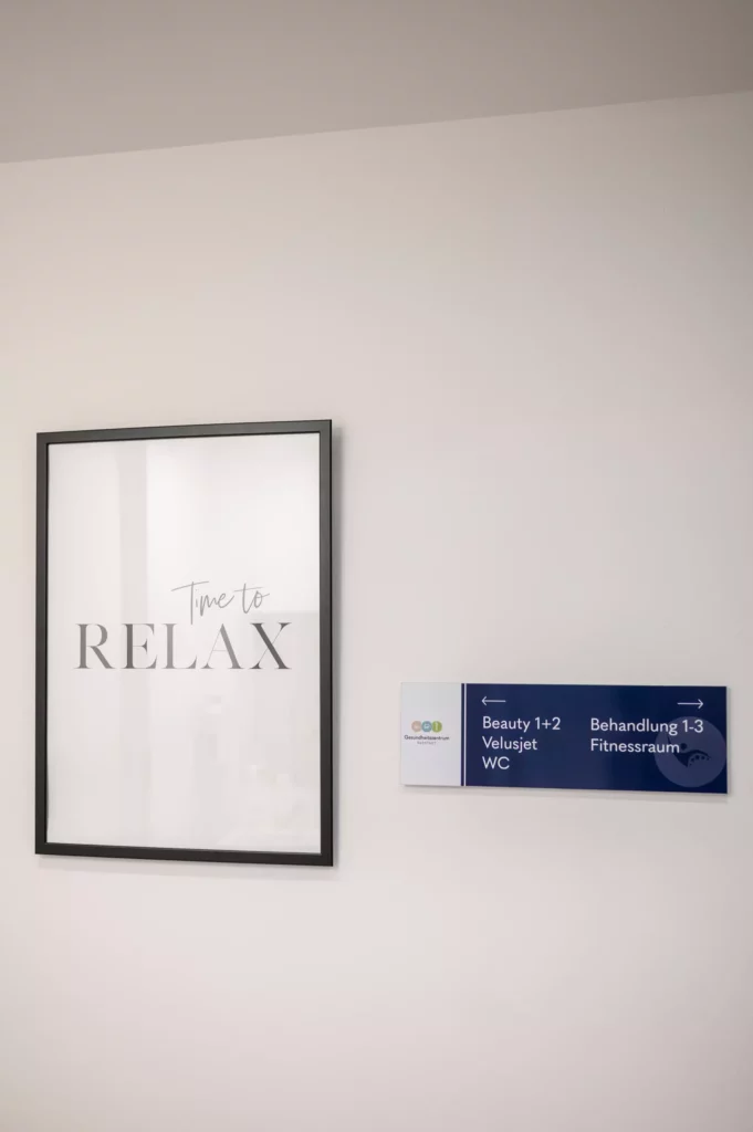 Wand mit schwarzem Rahmenbild Time to RELAX und blauem Wegweiser zu Beauty, Velusjet, WC, Behandlung und Fitnessraum im