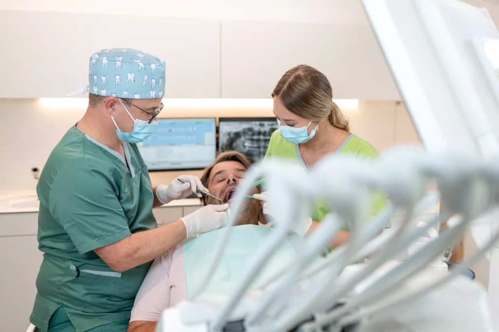 Zahnarzt und Assistentin behandeln Patienten im Behandlungsstuhl in moderner Praxis für Kieferchirurgie Radstadt.